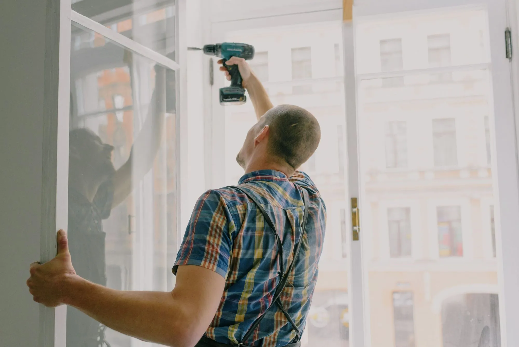 Fagmann justerer vindusramme med drill